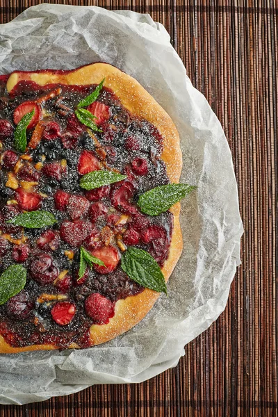 A round tart with berries in the wooden background — Stock Photo, Image