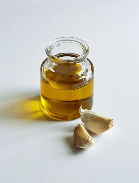 A jar of oil and two garlic cloves — Stock Photo, Image