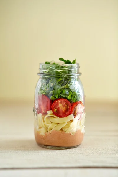 pasta with dressing, tomatoes and rocket leaves