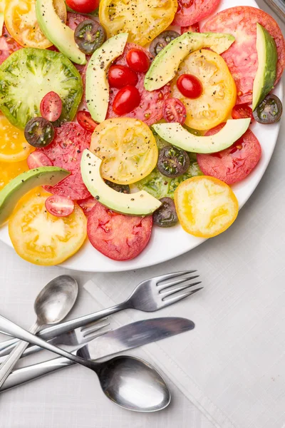 Tomatoe and avocado slices on white plate — Stock Photo, Image