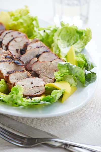 Gegrillte Schweinescheiben serviert mit Salat und Mango — Stockfoto