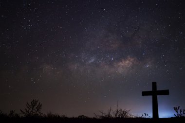 Silhouette of cross over milky way background,Long exposure photograph clipart