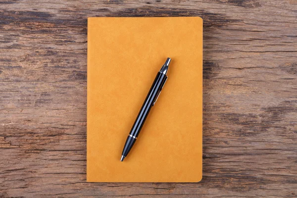 Blank yellow note pad with pen on wood background — Stock Photo, Image