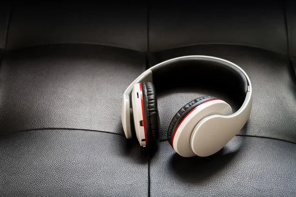 Bluetooth headphones on black leather background — Stock Photo, Image