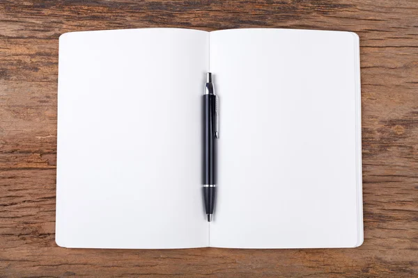 Blank note pad with pen on wood background