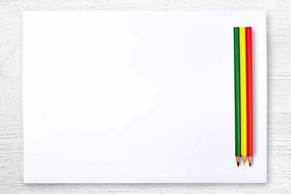 Beyaz kağıt ve renkli kalem üzerinde beyaz ahşap masa, üstten görünüm — Stok fotoğraf