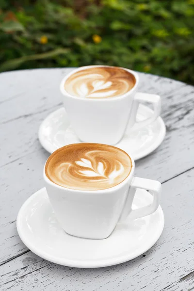 Taza de café con leche sobre mesa de madera blanca — Foto de Stock