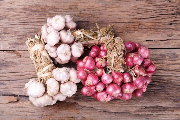 Cipolle rosse con aglio intero su fondo legno — Foto Stock