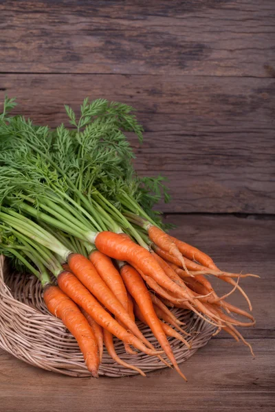 Куча свежей моркови с зелеными листьями на деревянной спинке — стоковое фото
