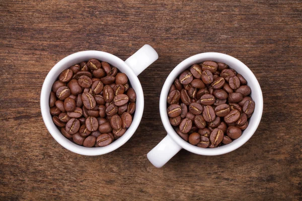 Cup of coffee beans on the brown wooden background — Stock Photo, Image