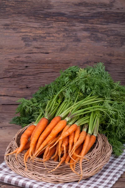 Mazzo di carote fresche con foglie verdi su sfondo di legno — Foto Stock