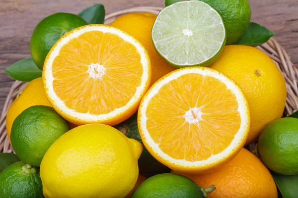 Mix of fresh citrus fruits in basket on  wood — Stock Photo, Image