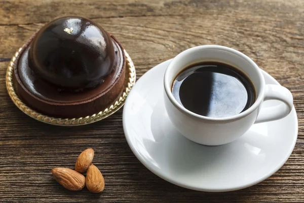 Кофе с шоколадным тортом и миндалем на деревянном фоне — стоковое фото