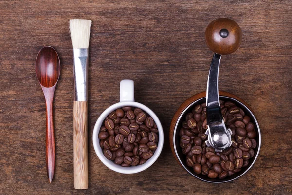 Cup of coffee beans and spoon on the brown wooden background — Stock Photo, Image