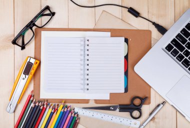 Çalışma alanı ile renkli kalemler ve malzemeleri, laptop, dizüstü, gözlük camı üzerinde ahşap tabl