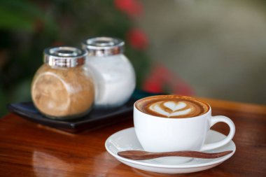 Mavi ahşap masada bir fincan latte.