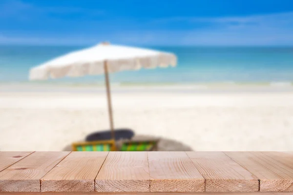 Mesa de madera sobre fondo azul borroso y playa de arena blanca — Foto de Stock