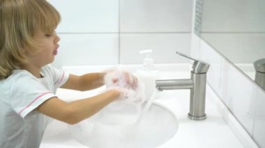 Küçük çocuk ellerini sıvı sabunla yıkıyor..