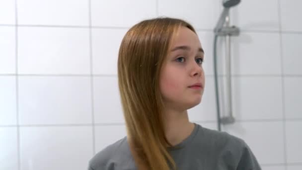 Привлекательная молодая женщина расчесывает здоровые длинные волосы деревянной расческой — стоковое видео