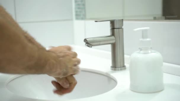 Zapobieganie koronawirusom. Mężczyzna dokładnie myje ręce mydłem i ciepłą wodą w domu.. — Wideo stockowe