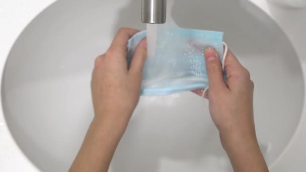 Ein Mann entfernt trockene medizinische Einweg-Mundschutz von einem beheizten Handtuchhalter für die Wiederverwendung während Covid-19. — Stockvideo