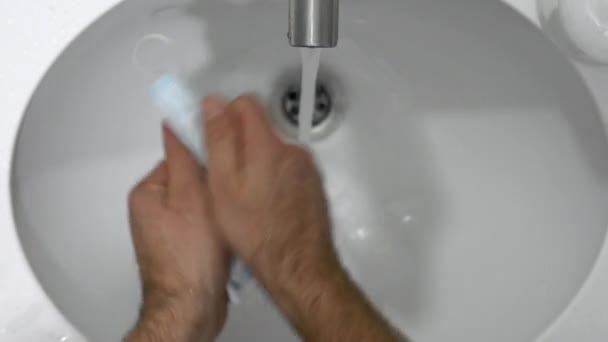 Manos de los hombres lavan mascarilla desechable con jabón para su reutilización debido a preocupaciones financieras. — Vídeo de stock