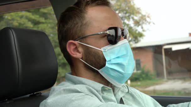 Ένας ενήλικας να οδηγεί αυτοκίνητο φορώντας προστατευτική μάσκα προσώπου κατά τη διάρκεια της επιδημίας του κορωναϊού.. — Αρχείο Βίντεο