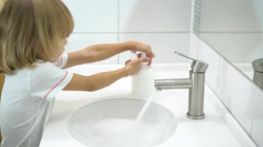 Küçük çocuk ellerini sıvı sabunla yıkıyor..