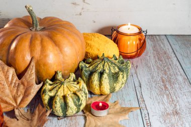 Şükran Günü arkaplanı, balkabaklarıyla kompozisyon, kuru sonbahar yaprakları, ahşap arka planda mumlar..