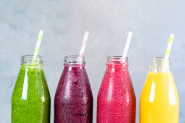 Yeşil, sarı, pembe ve kırmızı smoothie cam şişelerde