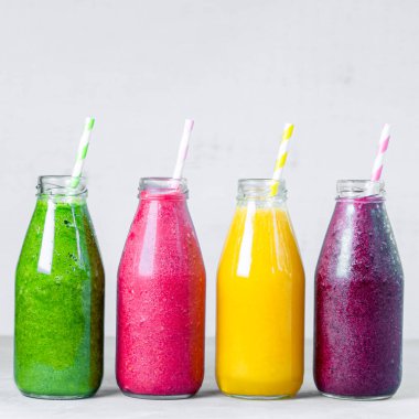 Yeşil, sarı, pembe ve kırmızı smoothie cam şişelerde