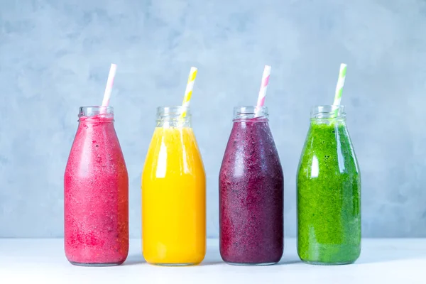 Yeşil, sarı, pembe ve kırmızı smoothie cam şişelerde