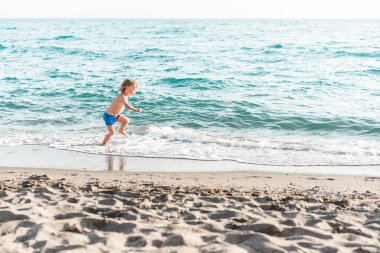 Deniz kıyısında oynayan ve eğlenen sevimli, komik bir çocuk. Yaz tatili, çocukluk hayatı, tatil seyahati.