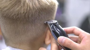 Çocuk saçını profesyonel bir kuaföre kestiriyor. Kapat.