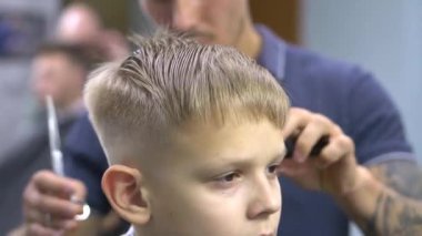 Bir kuaför profesyonel olarak bir genci keser. Kapat.