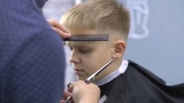 Erkek, profesyonel bir kuaför tarafından saçını kestiriyor.