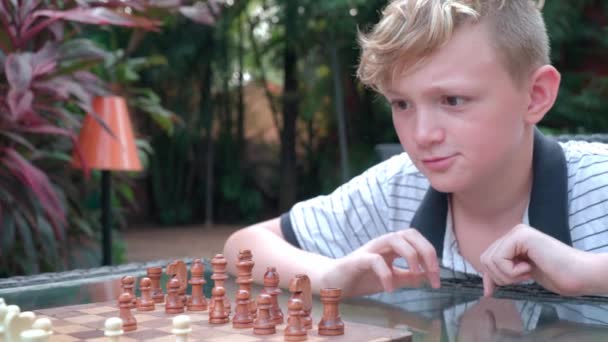 Junge überlegt, wie er seinen Freund im Schach gewinnen kann — Stockvideo