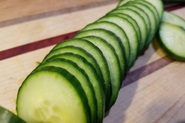 Salatalık dilimleri kesme tahtasının üstüne dizilmiş.