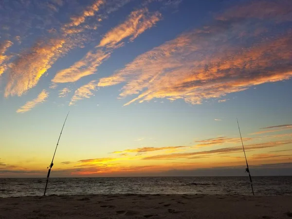 The silhouette of two surf fishing rods on the beach during early morning near Dewey Beach, Delaware, U.S.A