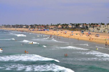 Sahile gidenlerin manzarası Huntingdon Beach, California, ABD yakınlarındaki büyük dalgaları bekliyor.