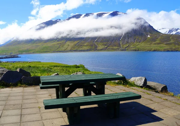 アイスランドのOlafsfjordur近くの夏に雪の山と青いフィヨルドを見下ろす空のピクニックテーブル — ストック写真