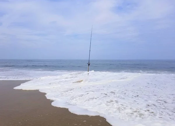 A surf fishing rod splashed by strong waves near Delaware Bay