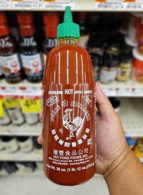 Delaware, ABD - 29 Ekim 2025 - 28 ons Huy Fong Gıda Şişesi Sriracha Hot Chili Sosu bir mağaza koridorunda tutuluyor.