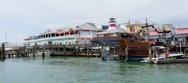 Madeira Sahili, Florida, ABD - 11 Kasım 2025 - Canlı kıyı şeridi John Pass Boardwalk Restoranlar, korsan gemisi, deniz feneri ve hareketli bir turizm merkezinde paraşütle atlayan tekneler.