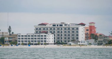 Madeira Sahili, Florida, ABD - 11 Kasım 2025 - Cambria Oteli ve komşu tatil beldeleri bulutlu gökyüzünün altında şemsiyeler, sandalyeler ve okyanus manzaralı kumsala bakar.