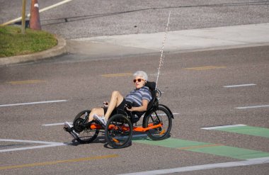 St Petersburg, Florida, ABD - 2 Ocak 2026 - Turuncu-siyah üç şeritli yolda emniyet bayrağı ve yeşil bisiklet şeridiyle bisiklet süren bir sürücü.