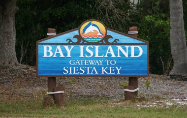 Siesta Key Beach, Florida, ABD - 3 Ocak 2026 - Körfez Adası tabelası, yunus amblemi ve kıyı temalı ahşap post tasarımı içeren Siesta Key 'e açılan manzaralı kapıyı gösteriyor