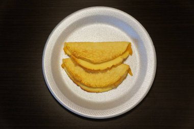 Eritilmiş peynirle dolu iki sarı omlet. Basit, lezzetli bir ev yapımı ikram için köpük tabakta servis ediliyor..