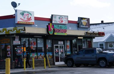 Wilmington, Delaware, ABD - 19 Ocak 2026 - Renkli bir mağaza vitrininde küçük bir plazada bir Meksika dondurmacısı ve bir pizza salonu yan yana