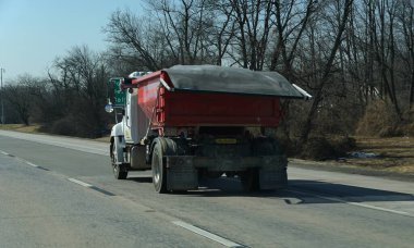 Wilmington, Delaware, ABD - 22 Şubat 2026 - Kırmızı bir çöp kamyonu kış otobanı boyunca yol güvenliği için malzeme taşıyor.